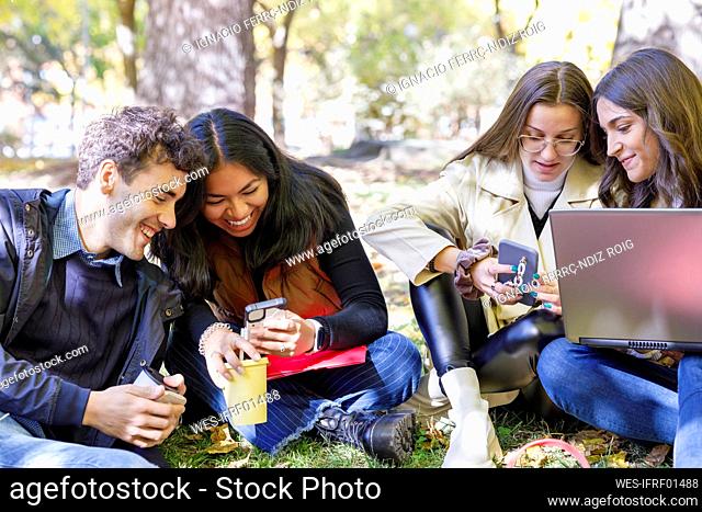 Women sharing smart phones with friends on campus