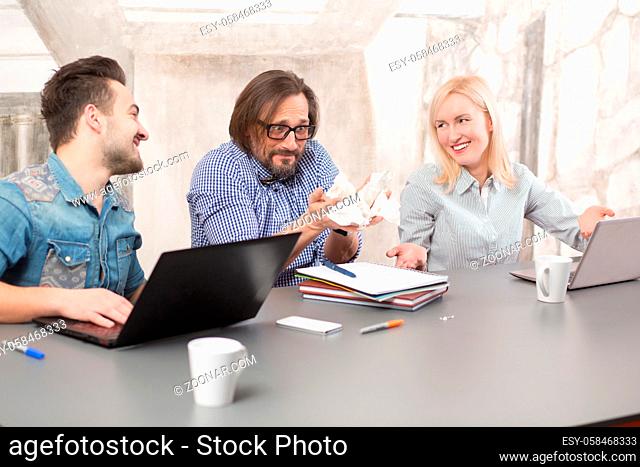 Business man and woman smiling and explaining their colleague that everything in fine and okay. Frightened man holding sheet of paper