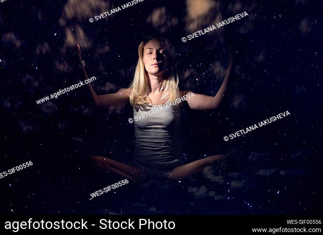 Woman with eyes closed meditating at night