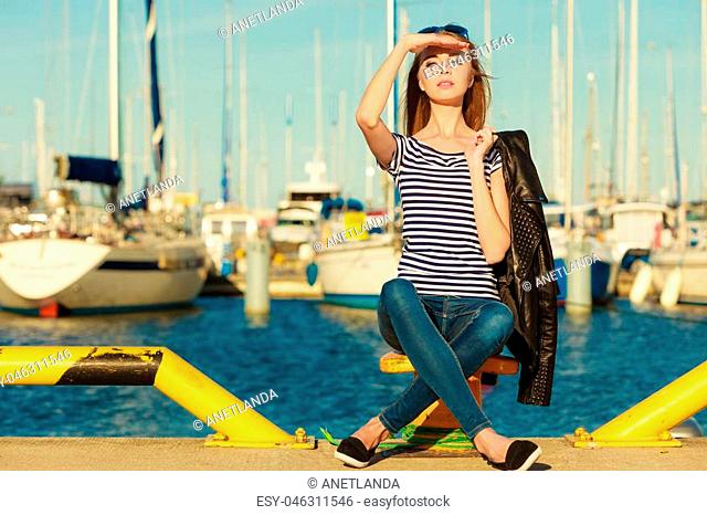 Tourism relax and people concept. Fashion blonde girl with blue heart shaped sunglasses in marina against yachts in port