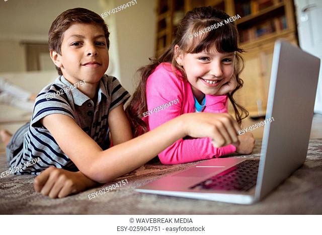 Siblings using laptop in living room