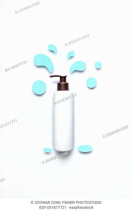 Creative concept photo of cosmetic bottle with splashing liquids made of paper on white background