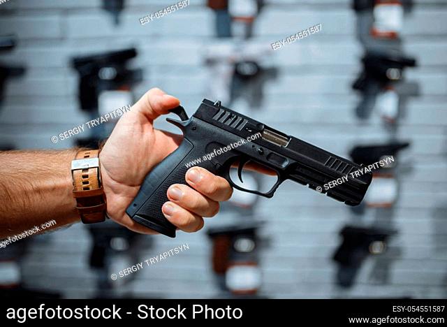 Man choosing new handgun at showcase in gun shop. Male person buying pistol for security in weapon store, selfdefence and sport shooting hobby