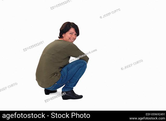 side view of a woman sitting squatting and looking at camera on white background