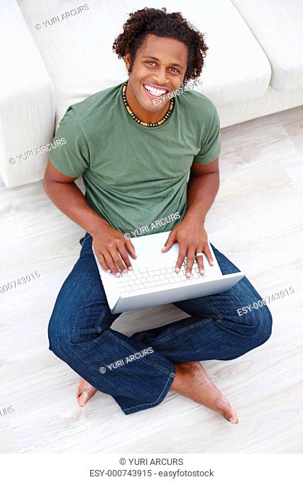 Young man relaxing on the floor with his laptop