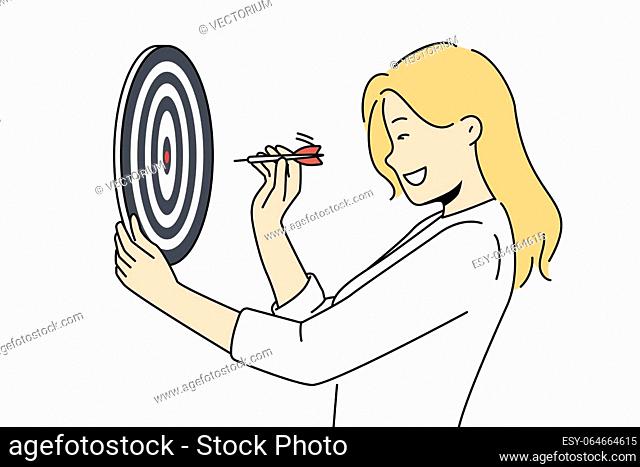 Determined woman throws darts at target for concept of business success and achieving set goals. Goal oriented businesswoman with darts board smiling setting...