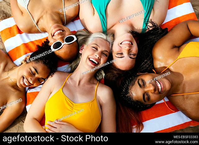 Multiracial friends lying down on beach towel