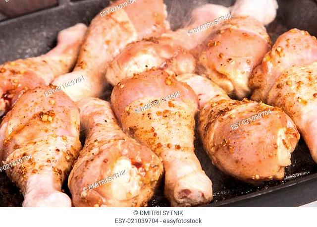 some raw chicken drumstick on frying pan