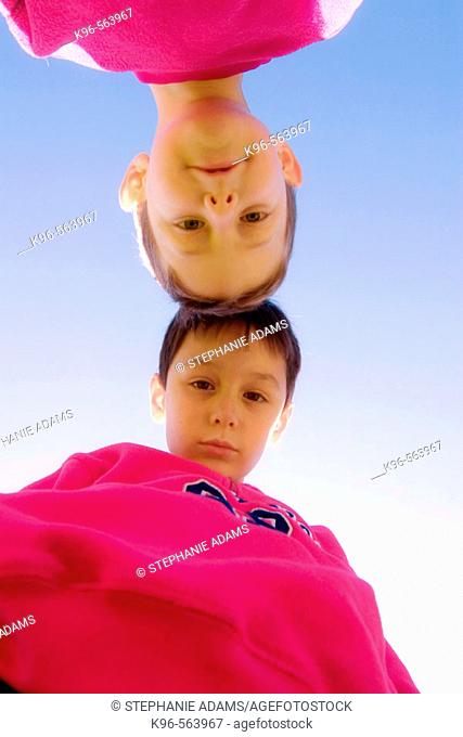 Two boys head to head looking down at camera