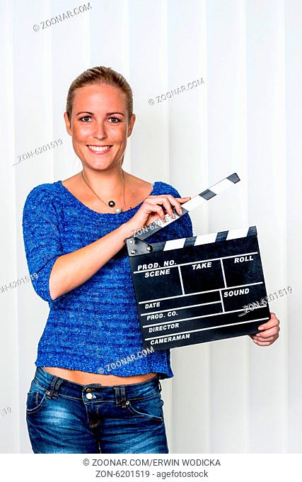 Eine Frau hält eine typische Filmklappe in ihrer Hand