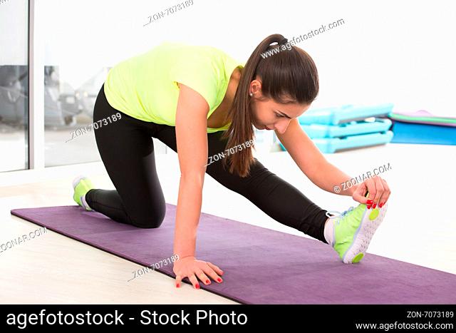 Young woman stretching on mat in sport gym