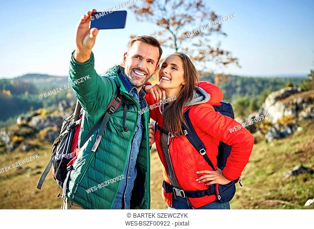 Happy couple on a hiking trip in the mountains taking a selfie