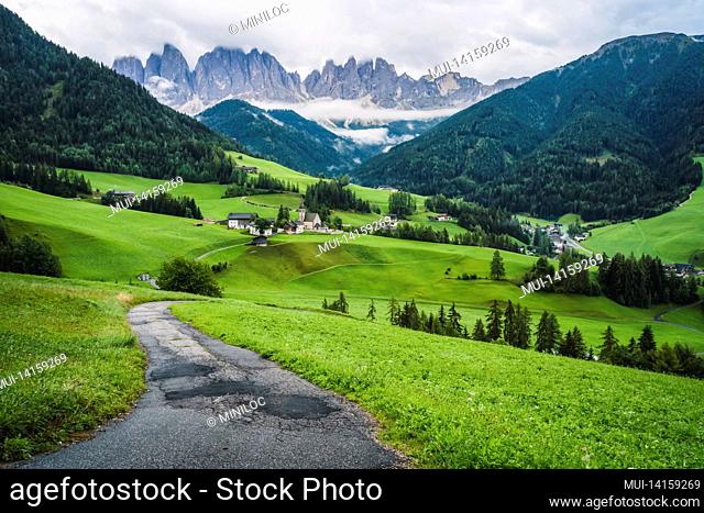 hiking trail to st magdalena church in val di funes valley, dolomites, italy. furchetta and sass rigais mountain peaks in background