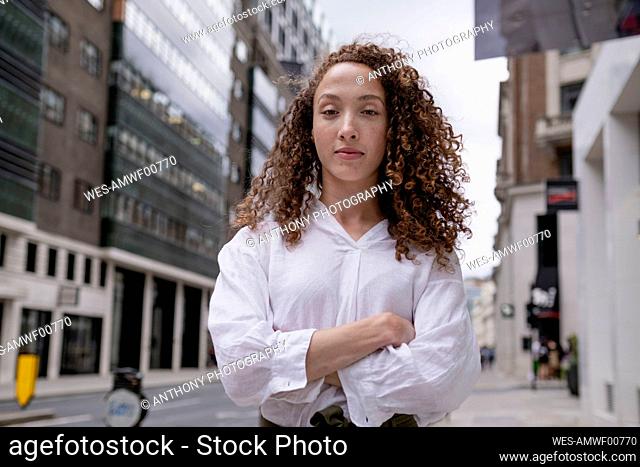 Young woman with arms crossed standing in city