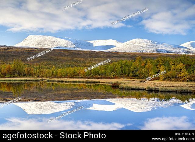Snowy mountains of Abisko National Park reflected in small pond, autumnal fell landscape, Abisko, Lapland, Sweden, Europe