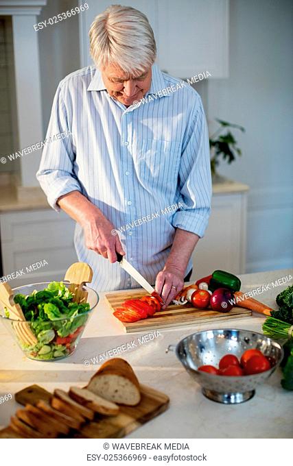 Senior man cutting vegetables for salad