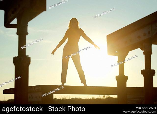 Silhouette woman standing with arms outstretched during sunset