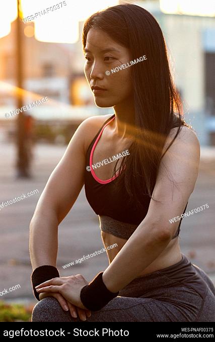 Dedicated woman in sports clothing exercising at park during sunset