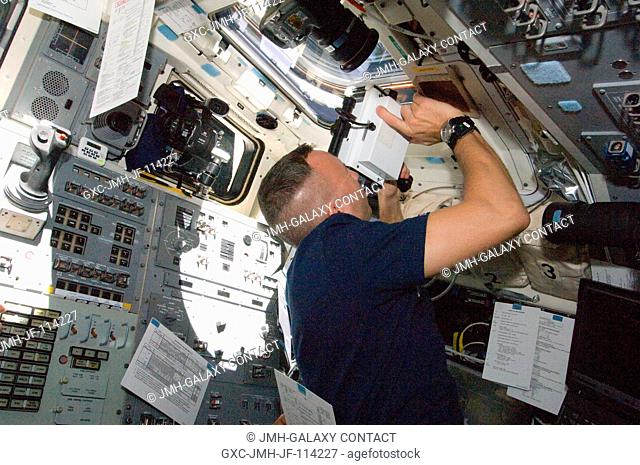 Astronaut Randy Bresnik, STS-129 mission specialist, uses a handheld laser ranging device -- designed to measure the range between two spacecraft -- through one...