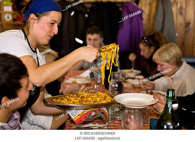 Woman serving pasta in mountain lodge Rifugio Agrituristico Salvin, Monastero di Lanzo, Piedmont, Italy