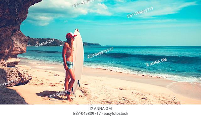 Sportive woman with surfboard on beautiful sandy coast, active hobby, waiting for a good waves, enjoying summer vacation on the beach
