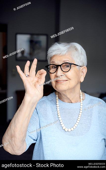 Smiling senior woman wearing eyeglasses showing OK sign gesture