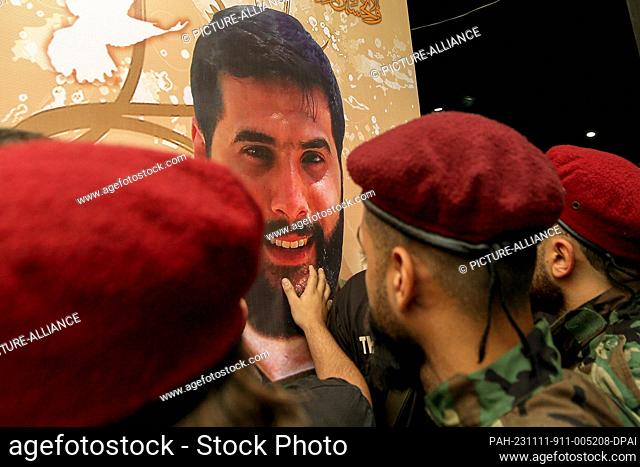 11 November 2023, Lebanon, Beirut: A Pro-Iranian Hezbollah militant touches the picture of his colleague, who was killed along with six other comrades