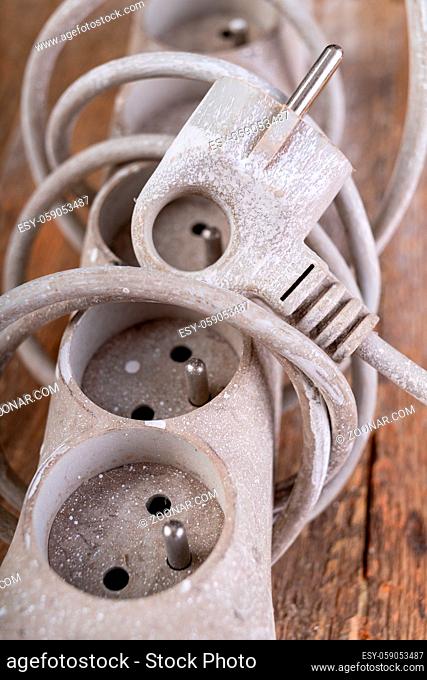 Old dirty extender on a wooden table. Electrical accessories in the workshop. Light background