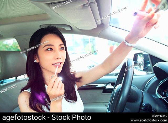 A beautiful young woman in the rearview mirror makeup