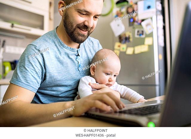 Father with baby son using laptop at home