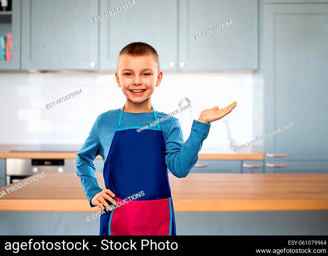 little boy in apron holding something on hand