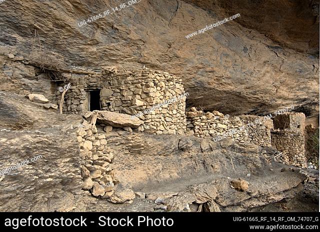 Stone huts of the deserted village of Sap Bani Khamis under a rock overhang in the Grand Canyon of Oman in Wadi an Nakhur, Jabal Akhdar mountains