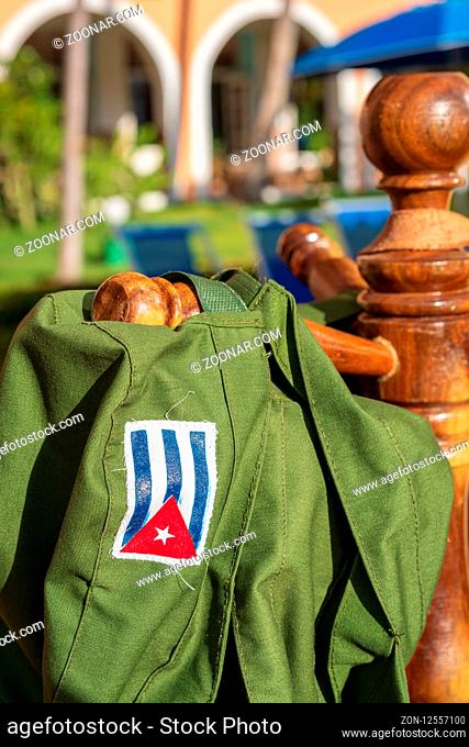 Green military hat with printed Cuban flag hanging in the sun, symbol of the Cuban revolution