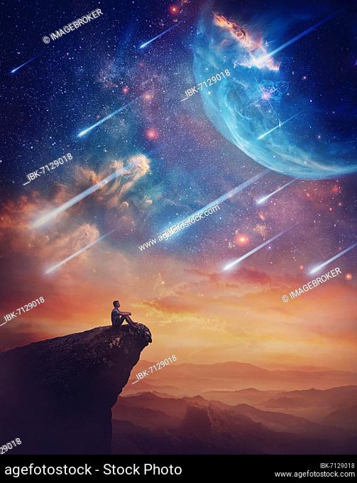 Lone person on the peak of a cliff admiring a wonderful space phenomenon. Fantastic scenery with falling stars and colorful nebulas above the sunset