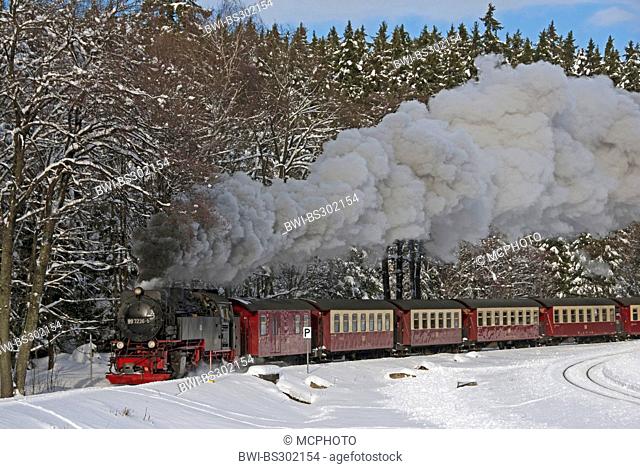 train of the Harzquerbahn going throug a snow-cowered Harz landscape in full steam; the narrow-gauge railwayconnects the cities Nordhausen (Thuringia) and...