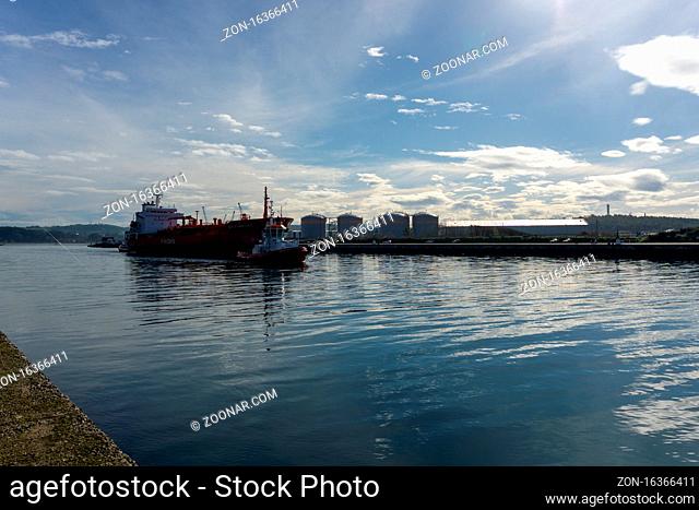 Avilés, Asturias / Spain - 7 November 2020: freight ship and tugboat on the Aviles River in northern Spain heading through the channel to the ocean