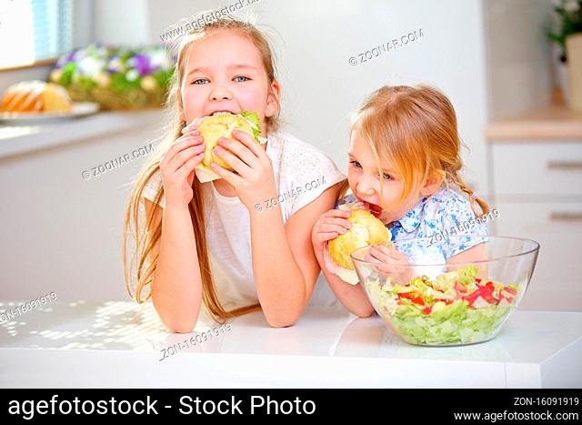 Zwei Kinder essen belegte Brötchen zum Frühstück in der Küche