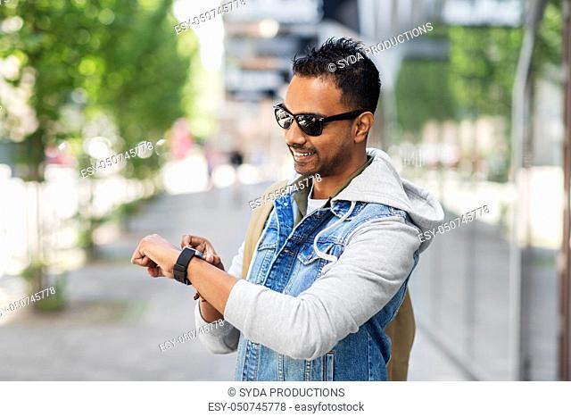 indian man with smart watch and backpack in city