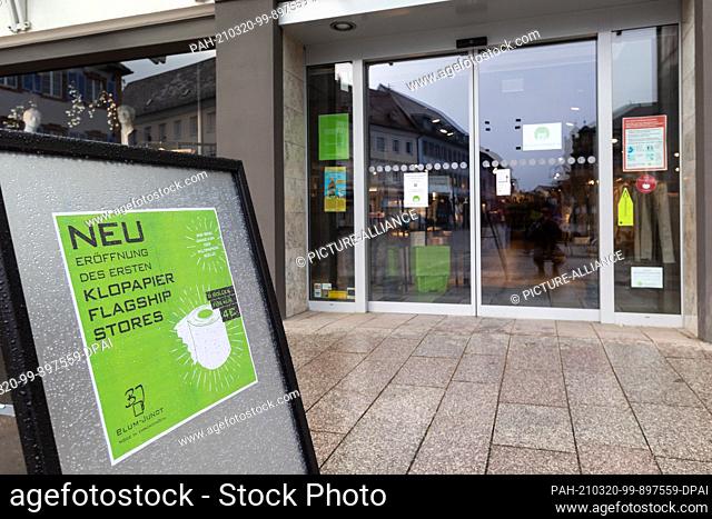 19 March 2021, Baden-Wuerttemberg, Emmendingen: A sign with the inscription ""New opening of the first toilet paper flagship store"" stands in front of the...