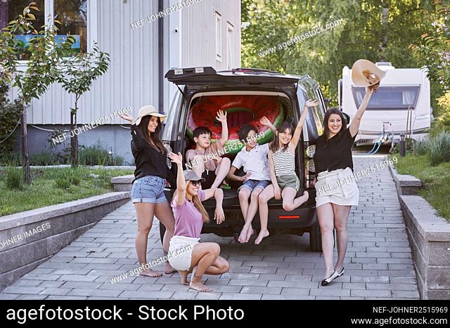 Women standing near car, children sitting in car boot