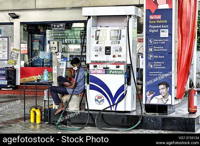 Kochi, India - May 2020: A gas station worker looks at his cell phone while wearing a mask on May 31, 2020 in Kochi, Kerala, India