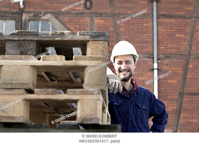 Smiling worker behind pallets