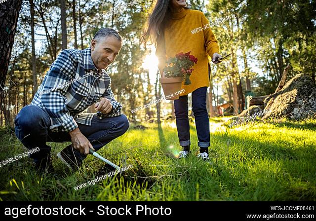 Mature couple planting flower in natural garden