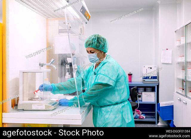 Female scientist measuring powder medicine on scale in laboratory