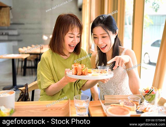 Happy girlfriends having lunch together at restaurant