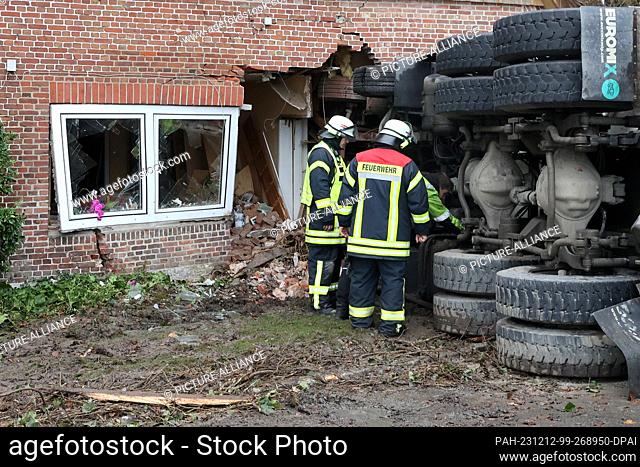 12 December 2023, Schleswig-Holstein, Blomesche Wildnis: Emergency services stand next to a concrete mixer that has crashed into a house
