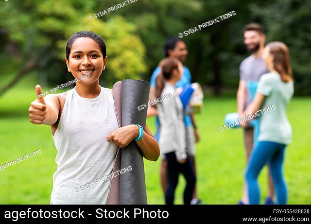 smiling woman with yoga mat showing thumbs up