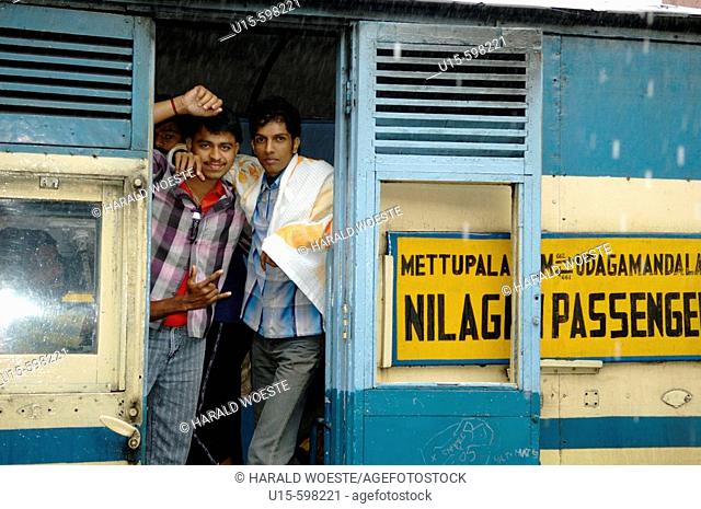 Loughing young indian men on board the Nilgiri Mountain Railway at Coonoor railway station in rain. India, Tamil Nadu, Coonoor 2005