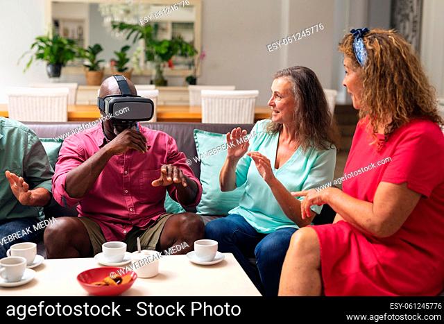 Multiracial senior women and man with male friend using vr headset at home