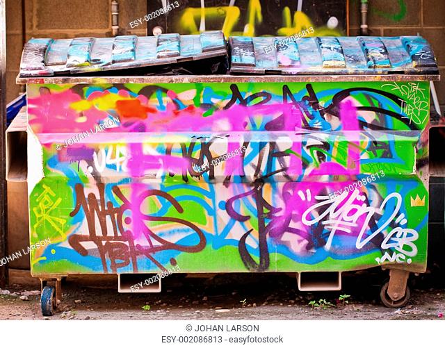 A rubbish bin or dumpster full of trash and covered in graffiti